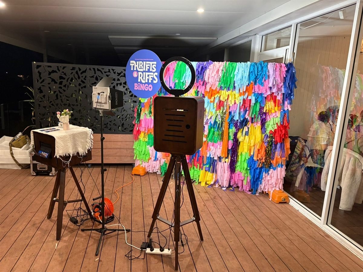 The Fotobooth Perth vintage booth, a dark timber cabinet on a wooden tripod with a ring light, set up beside its printer stand at a Perth event
